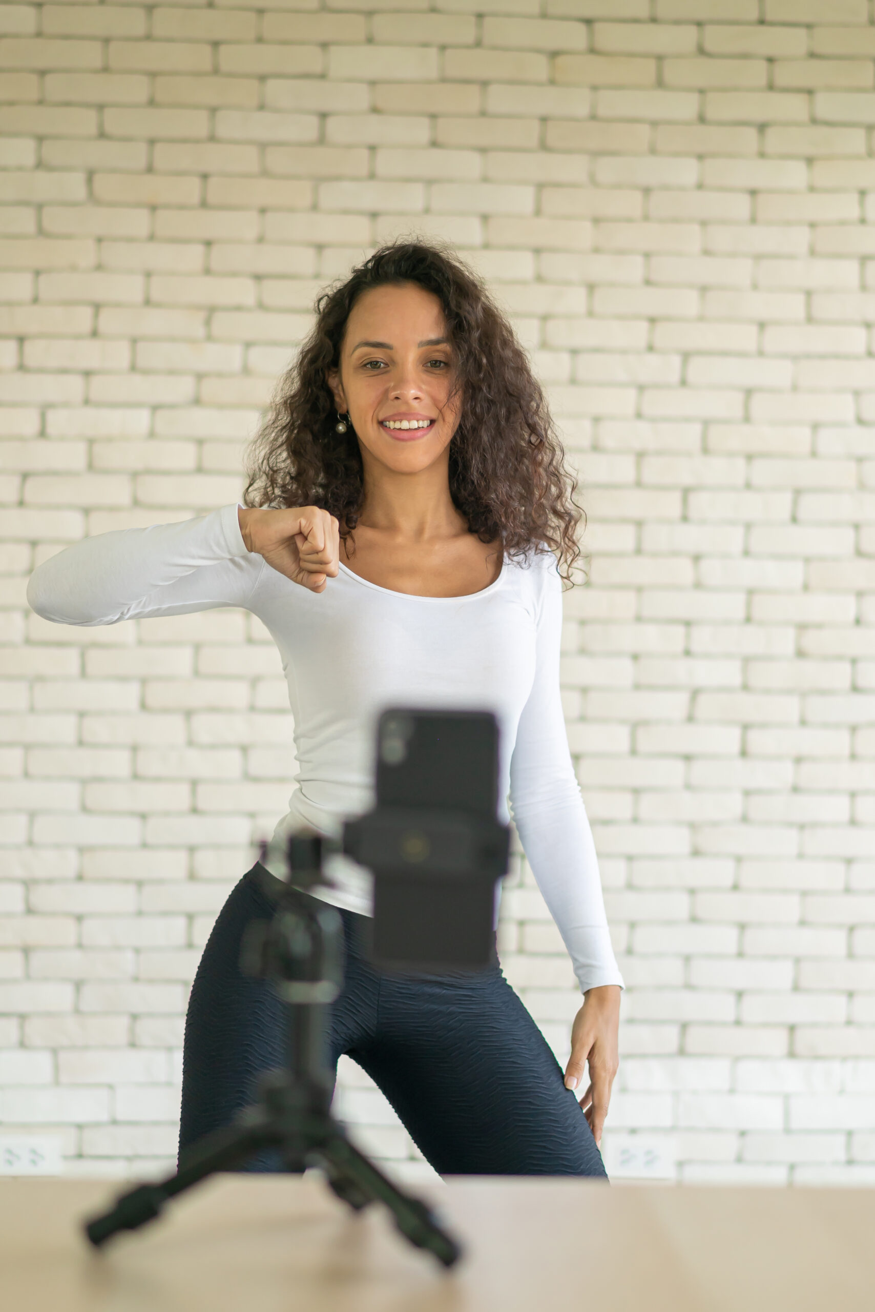 Latin woman influencer created her dancing video by smartphone camera. To share video to social media application.
